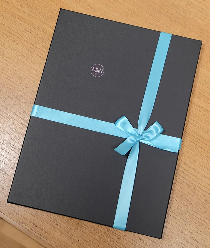 Close-up of a pencil pet portrait being wrapped in tissue paper inside its presentation box.