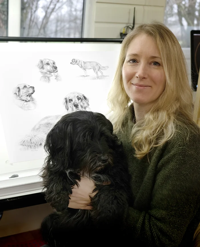 Melanie Phillips smiling with her Tibetan Terrier, Lily, inside their studio.