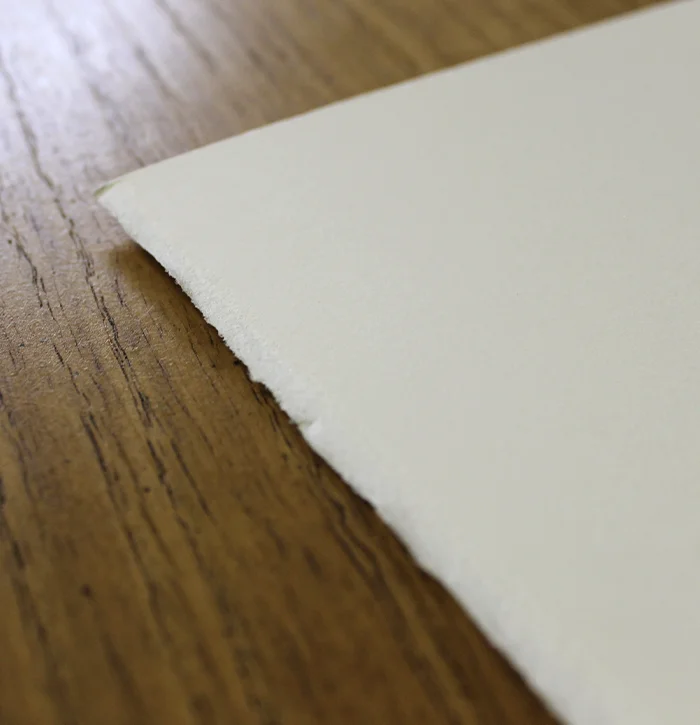 A close-up of high-quality Fabriano paper, showcasing its characteristic deckled edge and smooth surface.