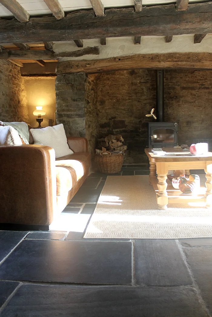 Warm and inviting Welsh cottage living room with a large inglenook fireplace and slate flagstone floor.