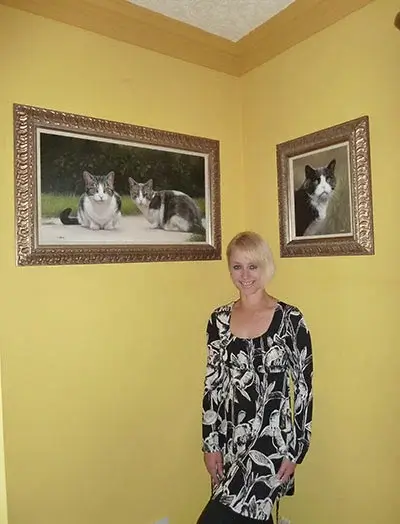 Client Amanda holding her new oil portrait of Purdy the cat, emotionally moved by its lifelike quality and detail.