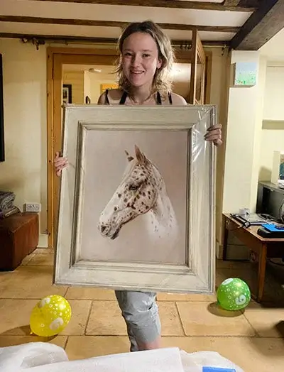 Happy client Craig's daughter joyfully receiving a custom oil portrait of her horse, beautifully framed and ready to hang.
