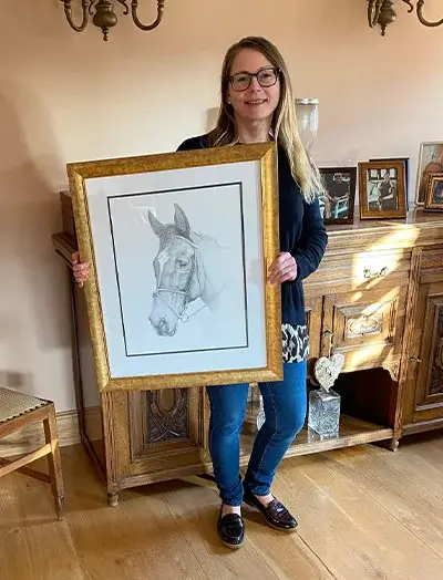 Client Phil Purssey's daughter reacting emotionally to her framed pencil portrait of Freya the horse, highlighting the portrait's accuracy.