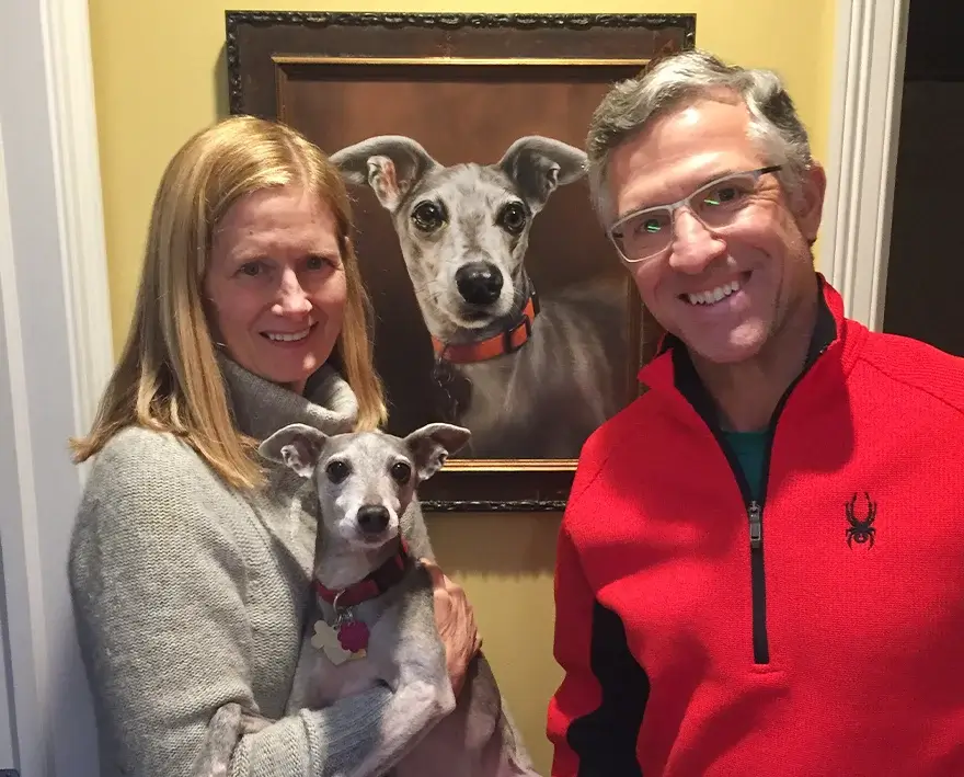 Artists Melanie and Nicholas posing with a newly completed oil portrait of Spyder, an Italian Greyhound, for client Karen.