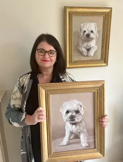 Client Sharon holding her new pet portraits of Bobby and Paddy, showcasing Nicholas's talent in capturing their likeness.